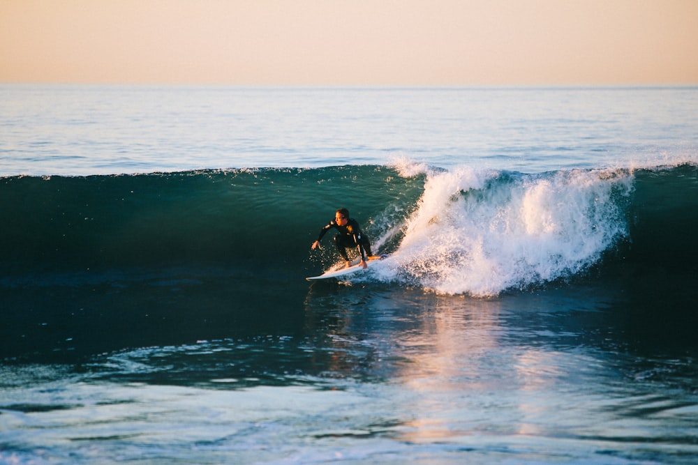 uomo che fa surf sull'onda dell'oceano durante il giorno