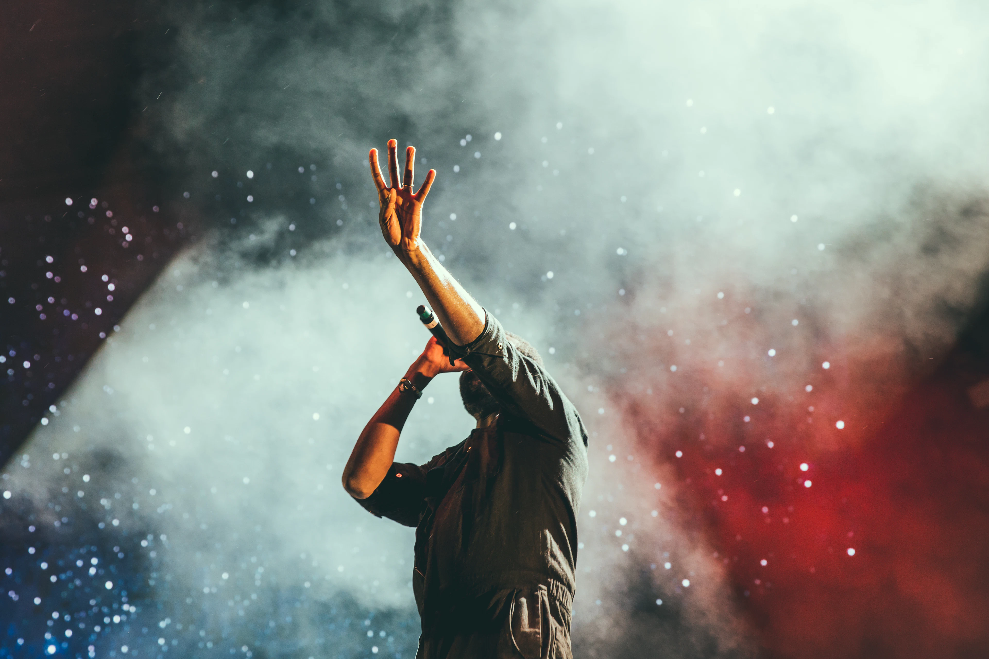 A figure lit by coloured smoke with arms raised
