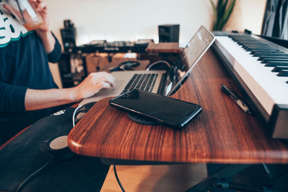 black Android smartphone beside MacBook Pro on top of brown table