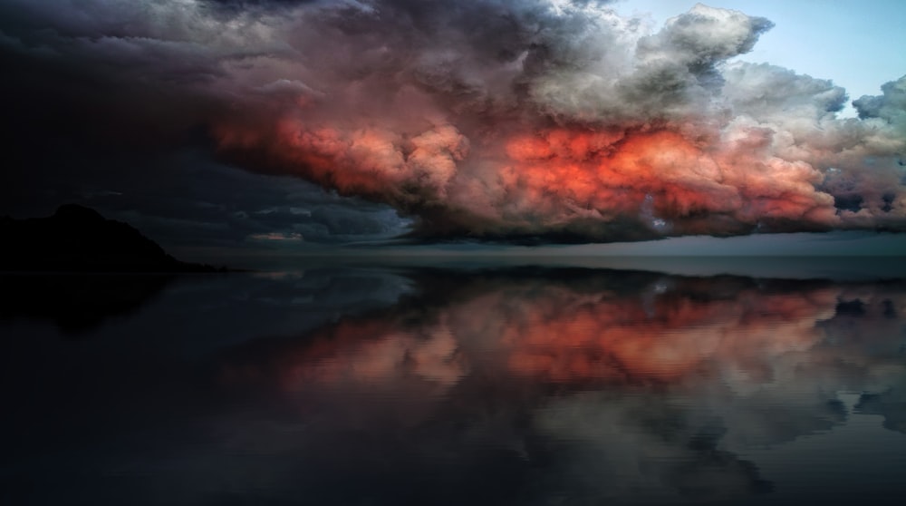 specchio d'acqua sotto nuvole rosse e bianche