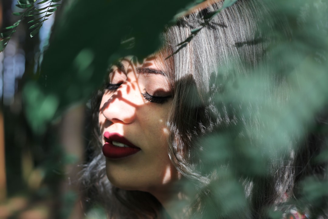 woman closing eye near leaf