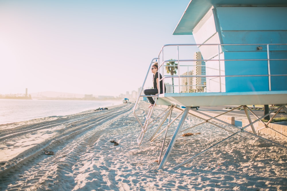 woman in black pants sitting on white ladder