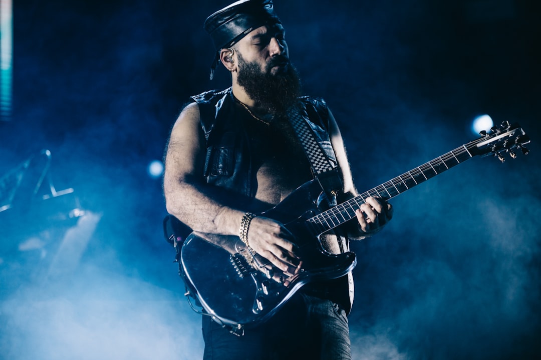 man in black tank top playing electric guitar