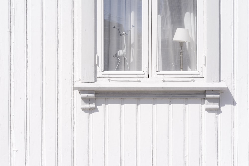 Armoire murale en bois blanc avec figurine et lampe de table à l’intérieur