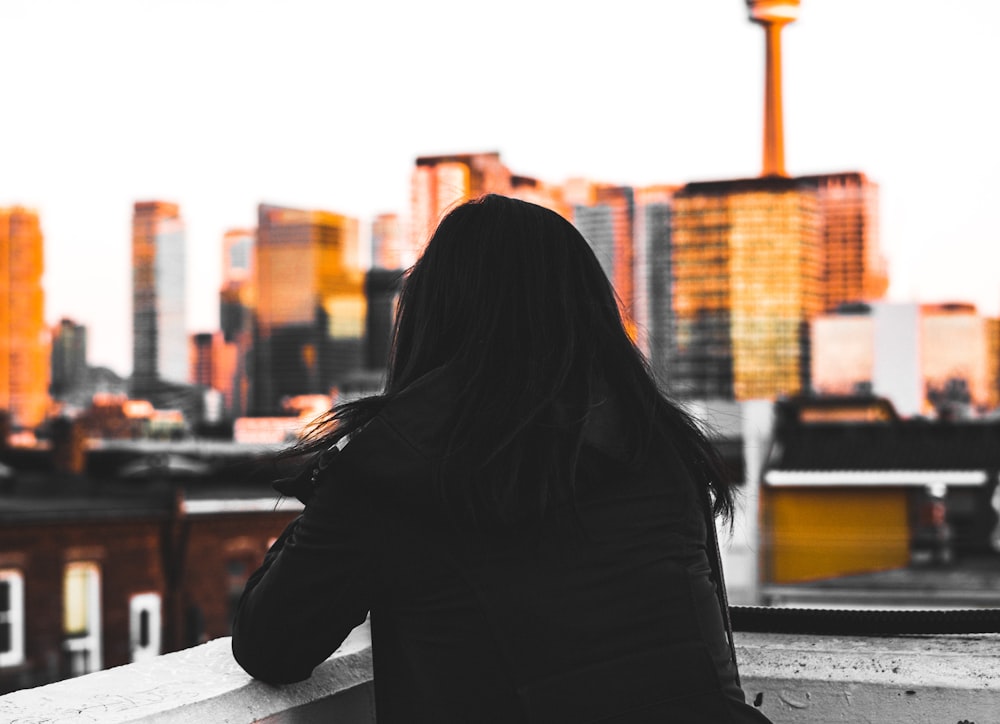 woman leaning on concrete wall looking at city