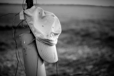 A stylish Celina Bobcats cap resting on a wooden bench near a football field