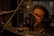 A person is singing passionately into a large microphone in a dimly lit recording studio. They are wearing headphones and are closely positioned to the microphone, emphasizing the intensity of their performance. The background features soundproofing curtains and studio equipment.