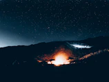Close-up of a warm campfire glow beneath a canopy of twinkling stars in Bhutan’s dark skies.