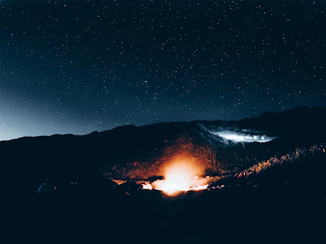 A cozy night campfire with friends laughing under starry mountains.