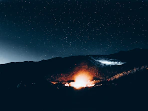 Close-up of a warm campfire glow beneath a canopy of twinkling stars in Bhutan’s dark skies.