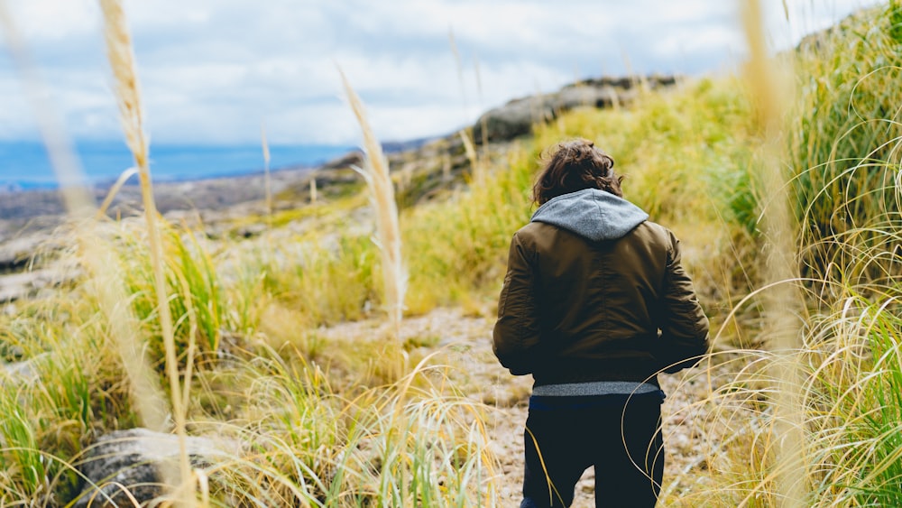 person standing on grass field near body of water