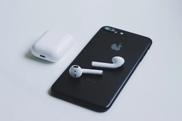 A sleek smartphone and wireless earbuds displayed on a clean white surface