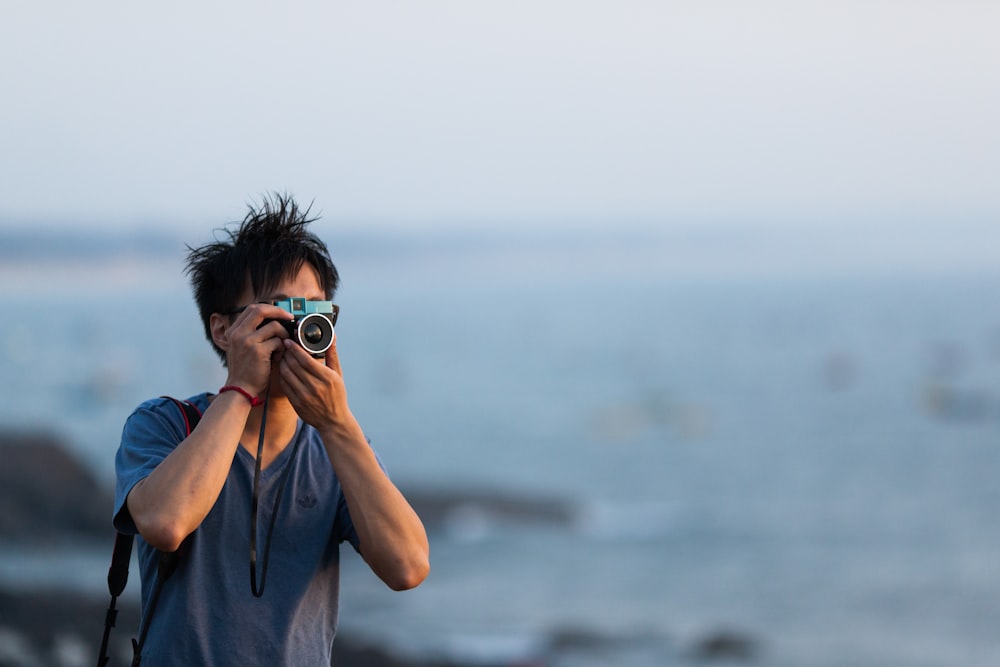 um homem tirando uma foto do oceano com uma câmera