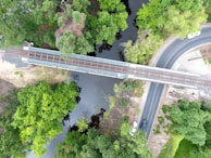 Aerial view of a Global Transport KFT truck crossing a large bridge over a river, surrounded by lush greenery.