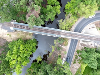 Aerial view of a Global Transport KFT truck crossing a large bridge over a river, surrounded by lush greenery.