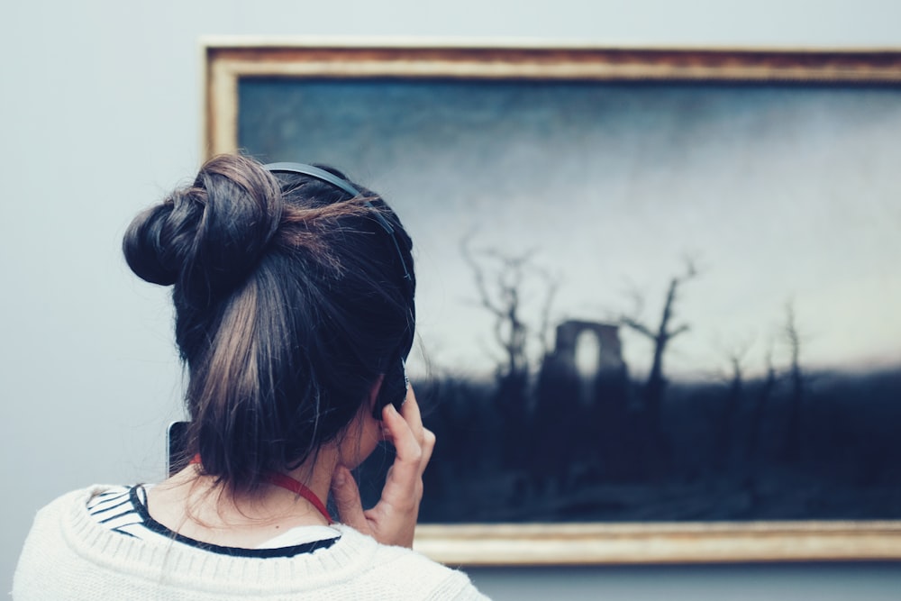 mulher olhando para uma pintura usando fones de ouvido