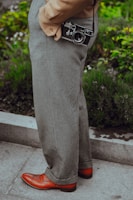 person wearing gray dress pants with camera