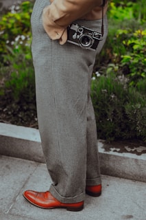 person wearing gray dress pants with camera