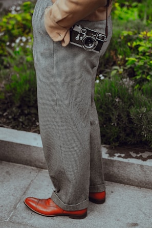 person wearing gray dress pants with camera