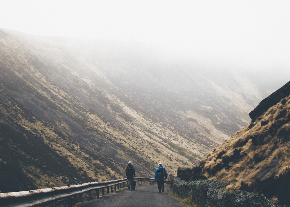 man wearing blue jacket walking on road