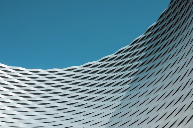 Undulating white façade forming continuous wave-like lines against the sky