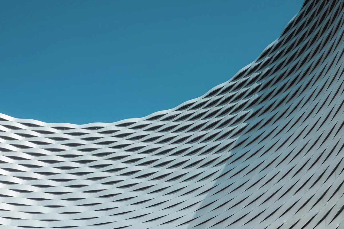 Undulating titanium museum facade with organic curves contrasting against a stark plaza