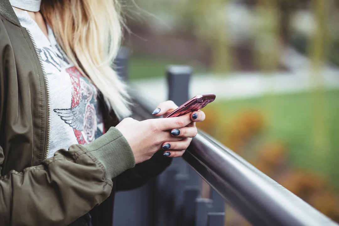 A person tapping a link on their phone outdoors on a bright day
