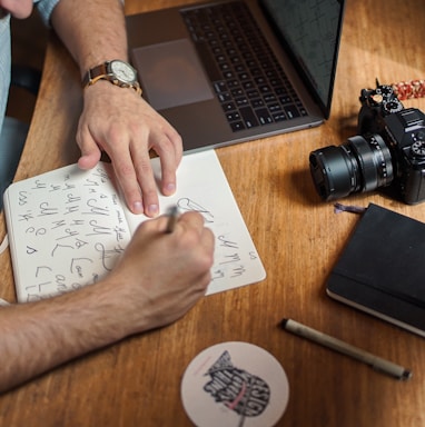 man writing on paper in front of DSLR