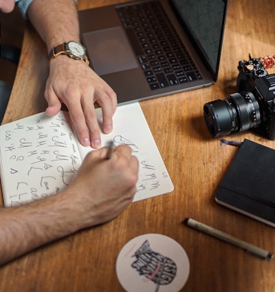 man writing on paper in front of DSLR