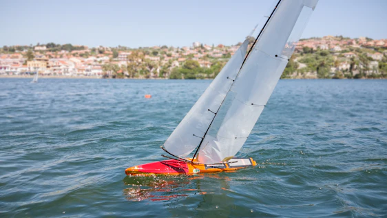 A sleek 3D printed RC sailboat model displayed on a digital blueprint background.