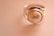 A close-up of a silver ring featuring a large, smooth pearl set in the center. The background is softly blurred in a warm, beige tone, emphasizing the elegance of the jewelry.