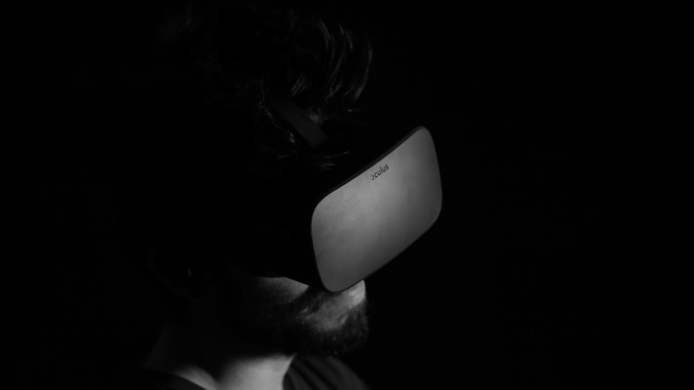 Foto in scala di grigi dell'uomo che usa il visore per la realtà virtuale
