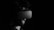 A person is wearing a virtual reality headset in a dimly lit environment. The image is in black and white, emphasizing the contrast between the dark background and the gadget. The person has a beard and short hair, and the headset partially obscures their face.