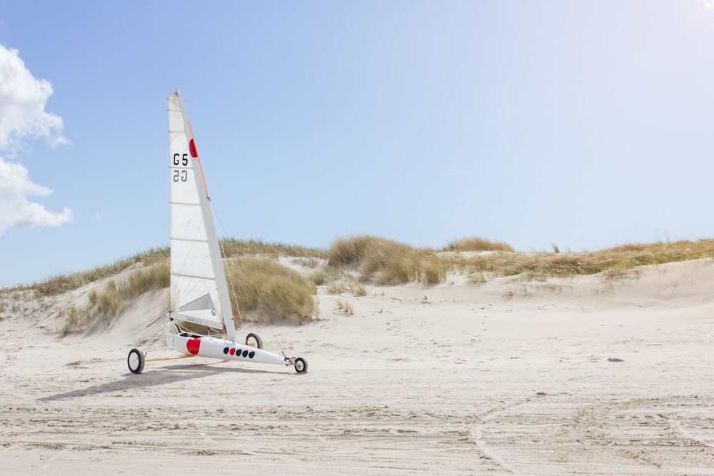 landscape photo of white sailboat with wheels on sand