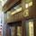 The image depicts the entrance to an office with large wooden doors and a prominent sign that reads 'Office of the Governor' in gold letters. The office is flanked by an American flag and features classical architectural elements, including columns and ornamental details. The atmosphere suggests a formal and official setting.