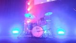 Drum set illuminated by stage lights, ready for a live concert