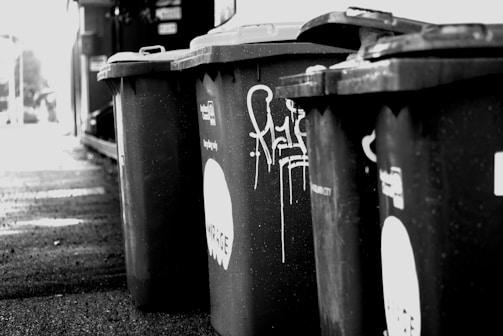 Various styles of metal trash bins displayed in an urban environment.