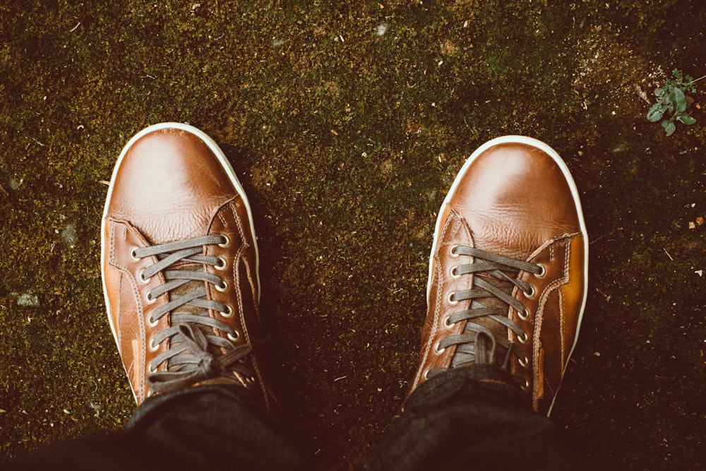 persona con zapatos de cuero marrón