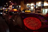 A row of taxis lined up ready for service under bright city lights at night
