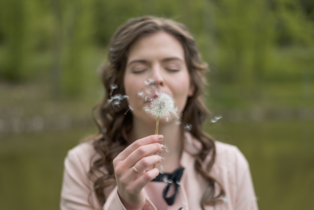 woman blowing dandelion flower