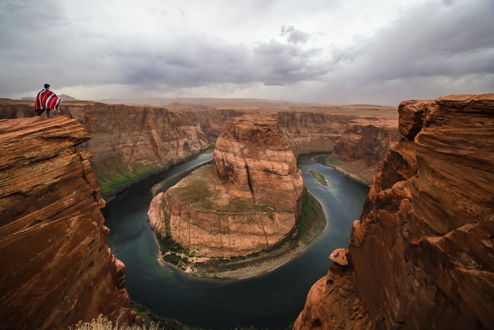 person standing on the edge a cliff during daytime