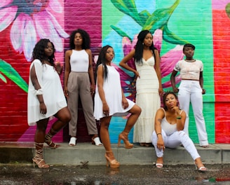 six women wearing white pants posing