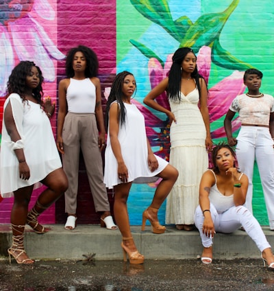 six women wearing white pants posing