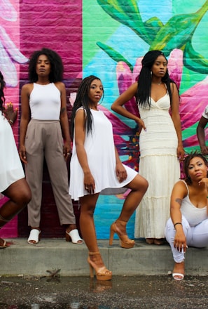 six women wearing white pants posing