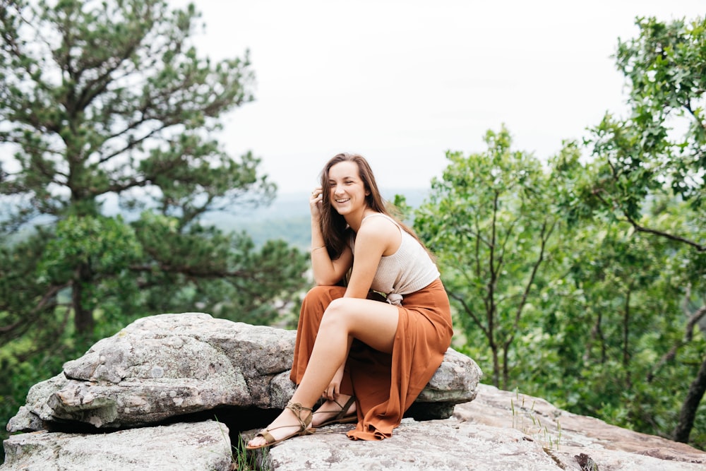 woman sitting on gray rock