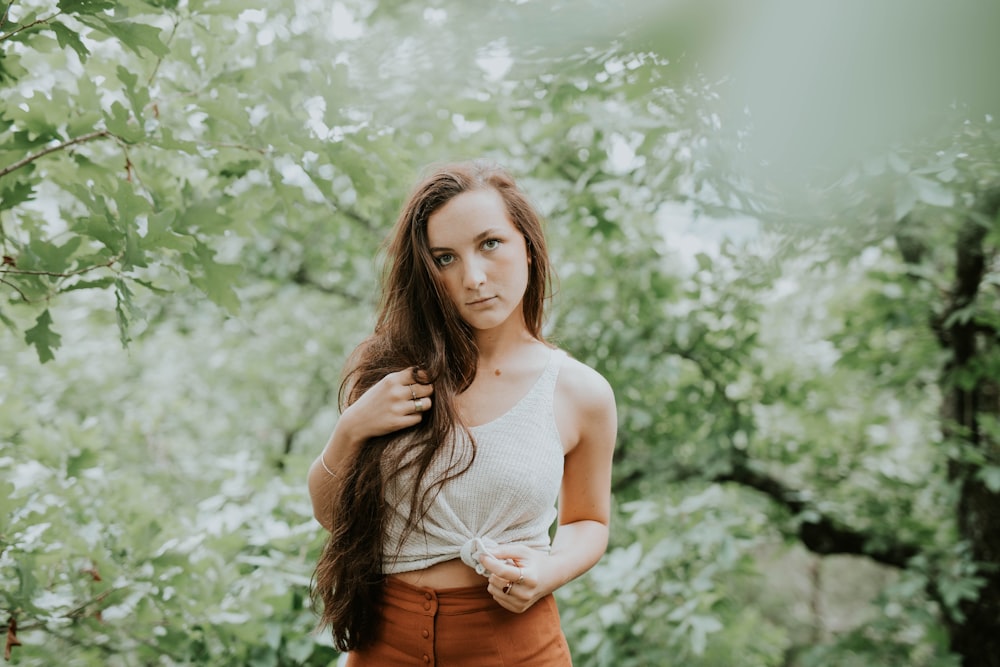fotografía de enfoque selectivo de mujer en camiseta sin mangas de pie en el bosque