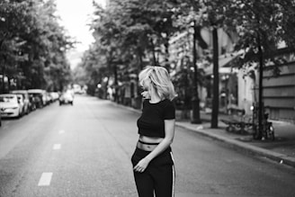 grayscale photo of woman leaning back standing on street