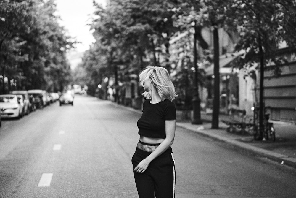 grayscale photo of woman leaning back standing on street