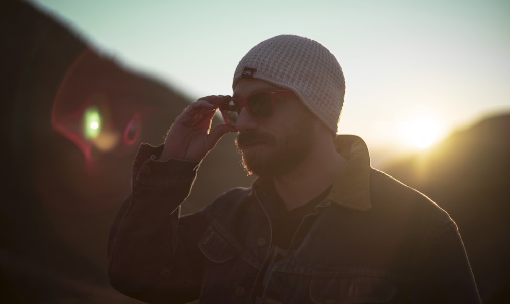 woman holding his sunglasses standing near mountain