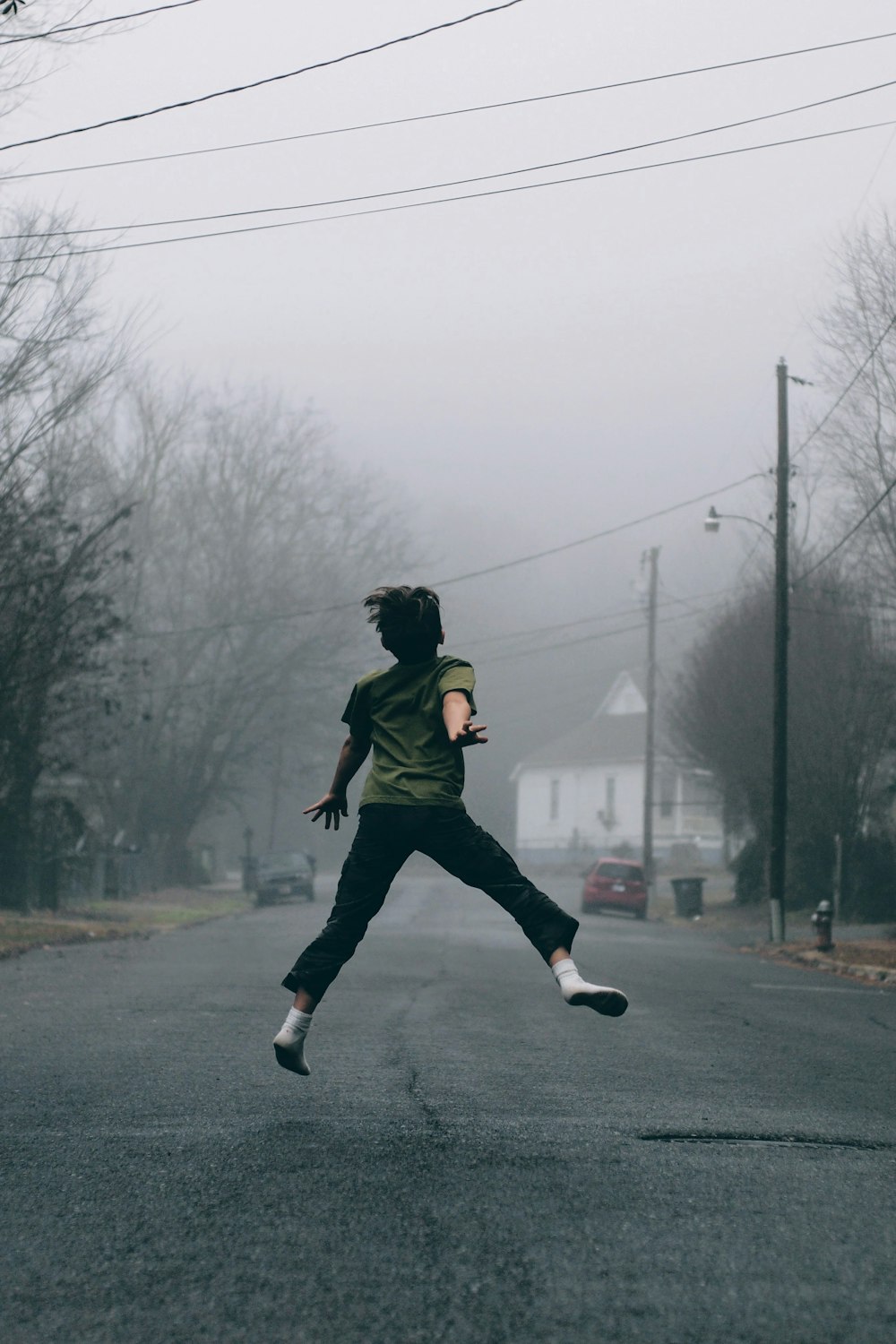 Niño salta en medio de la carretera en un día de niebla